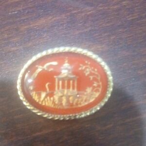 Vintage oval red glass or lucite brooch featuring a gold-tone Asian-style pagoda
